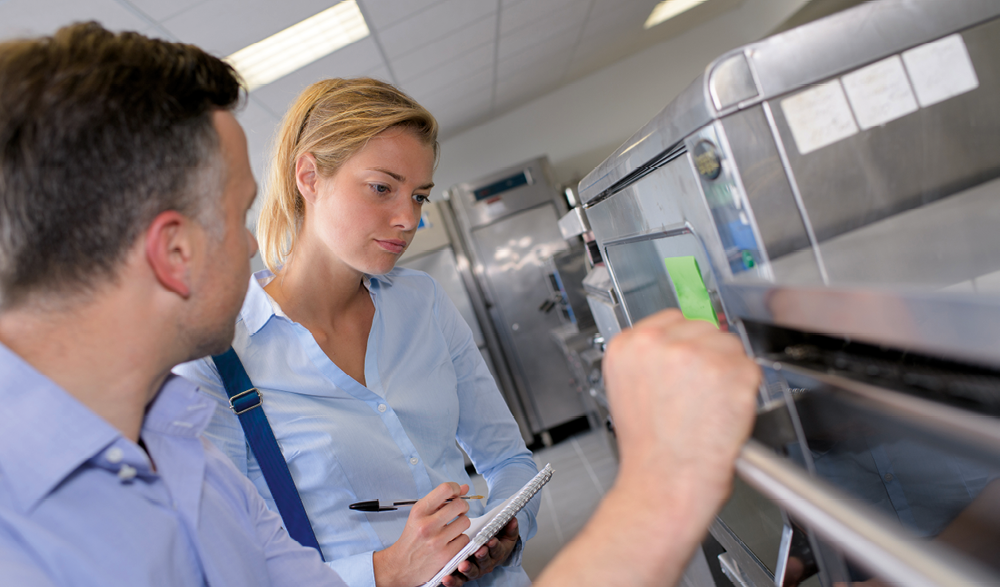 Woman inspecting kitchen, making notes